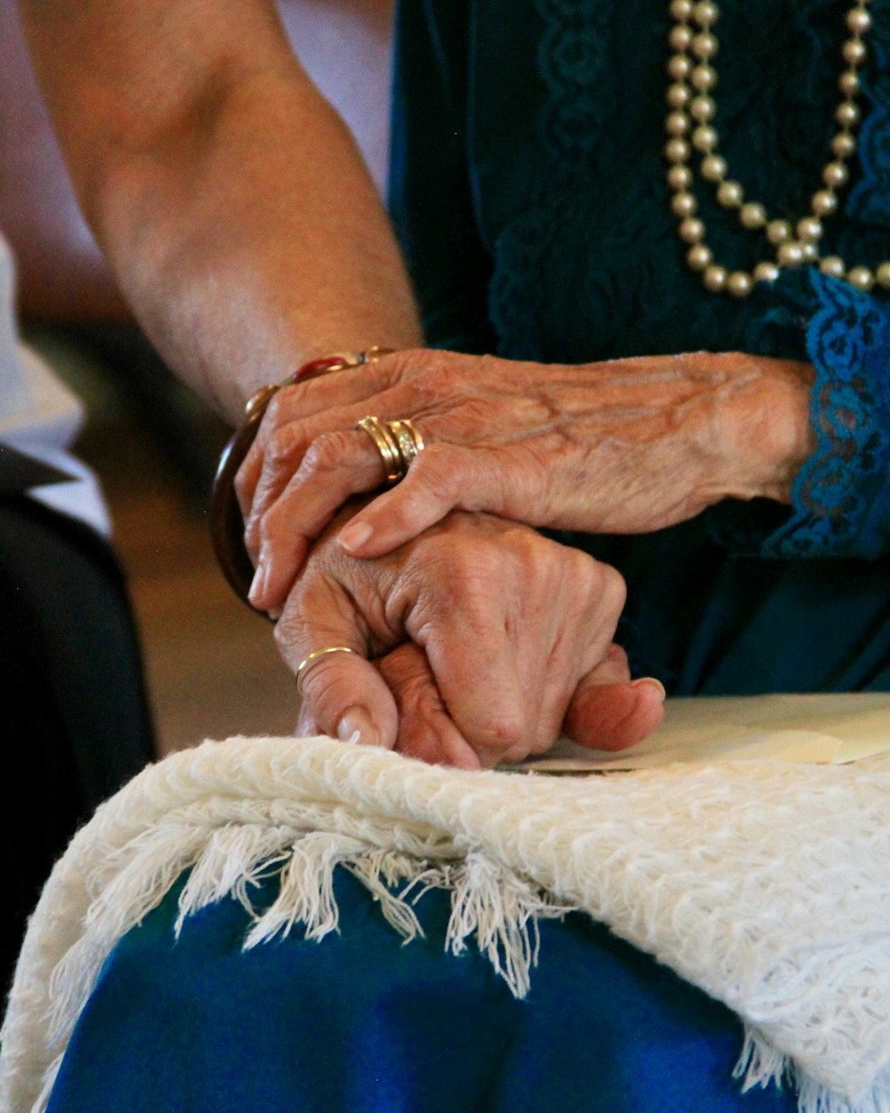 Une main se pose doucement sur les mains d'une femme âgée